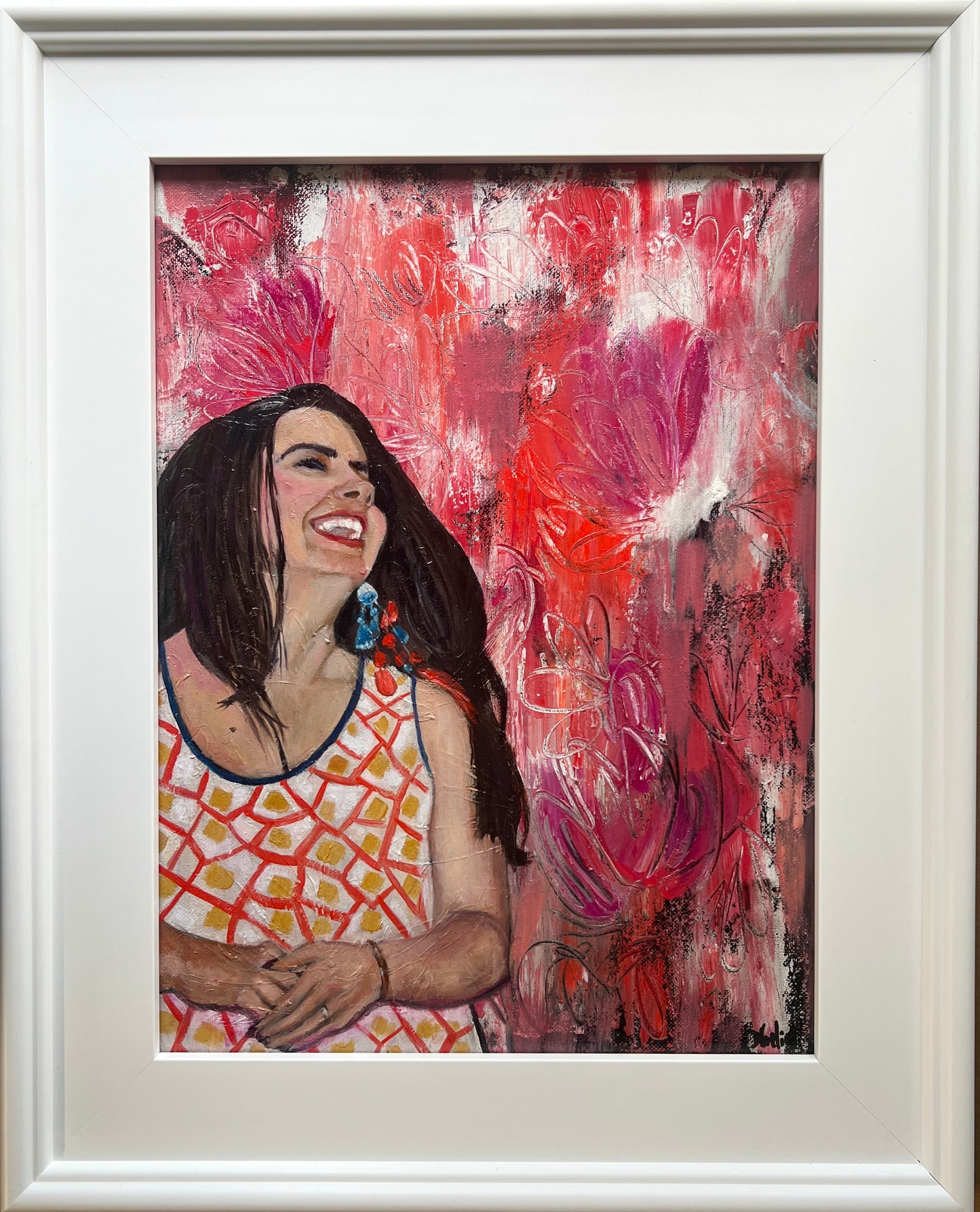 Oil Painting of Latina woman with long black hair lauging with bright orange and pink flowers in the background in a white frame